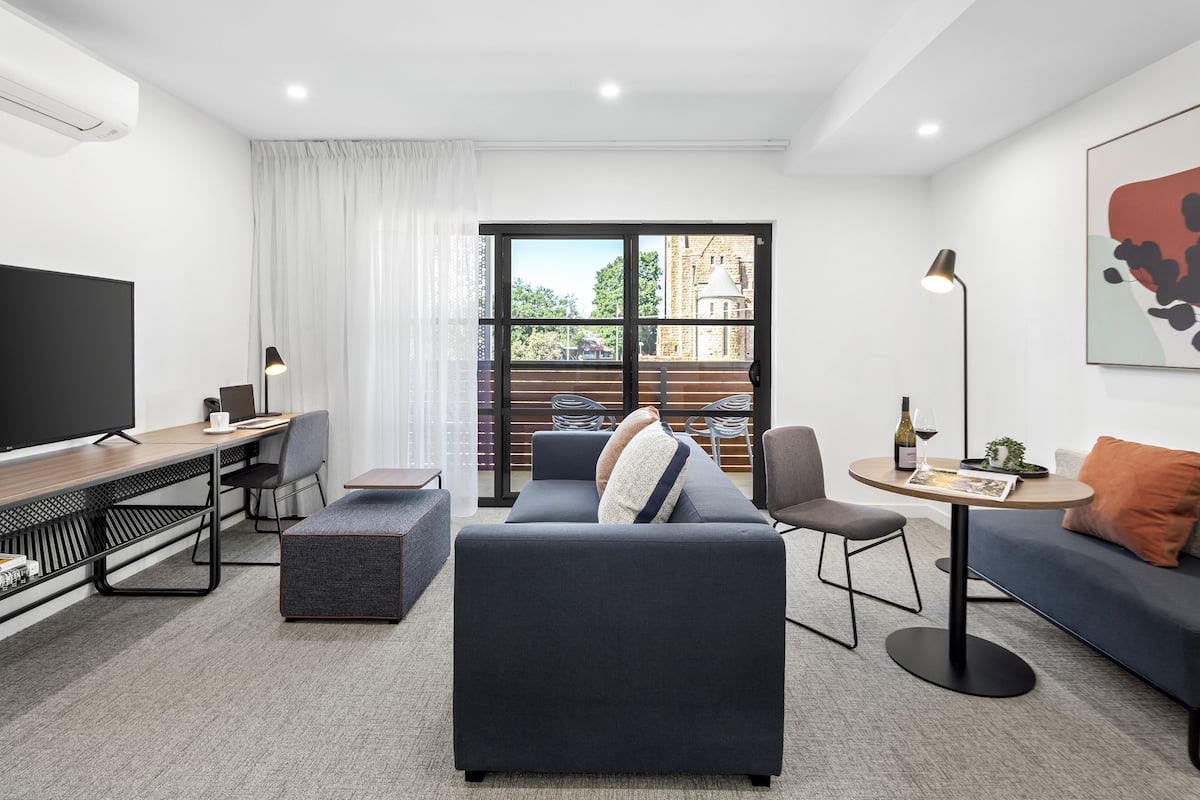 A modern living room with a sofa, a coffee table, a TV, and a dining area with a table and chairs.