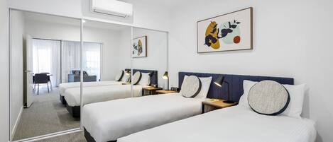 Habitación de hotel con dos camas, un espejo grande y obras de arte en la pared.