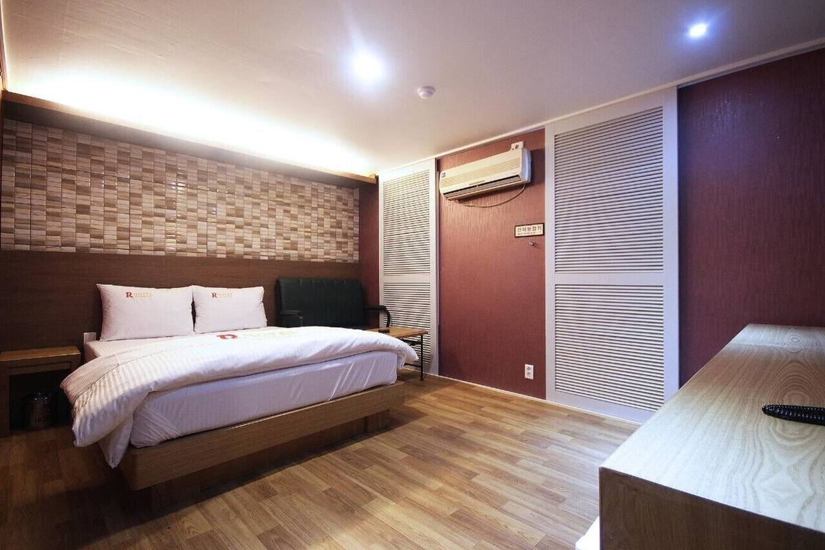 A modern bedroom with a wooden bed, a brick-patterned wall, and a sliding door closet.