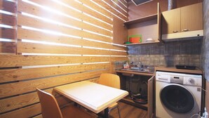 Cocina compacta con listones de madera, lavadora y un pequeño comedor.