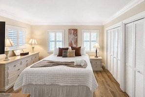 Une chambre à coucher comprenant un lit, des tables de chevet, une commode et un placard.