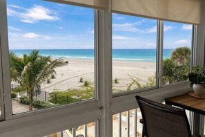 Una habitación con vistas a la playa, una mesa con una planta y una silla.