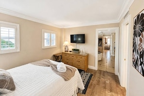 Une chambre à coucher avec un lit, une commode, une télévision et une vue sur la salle de bain.