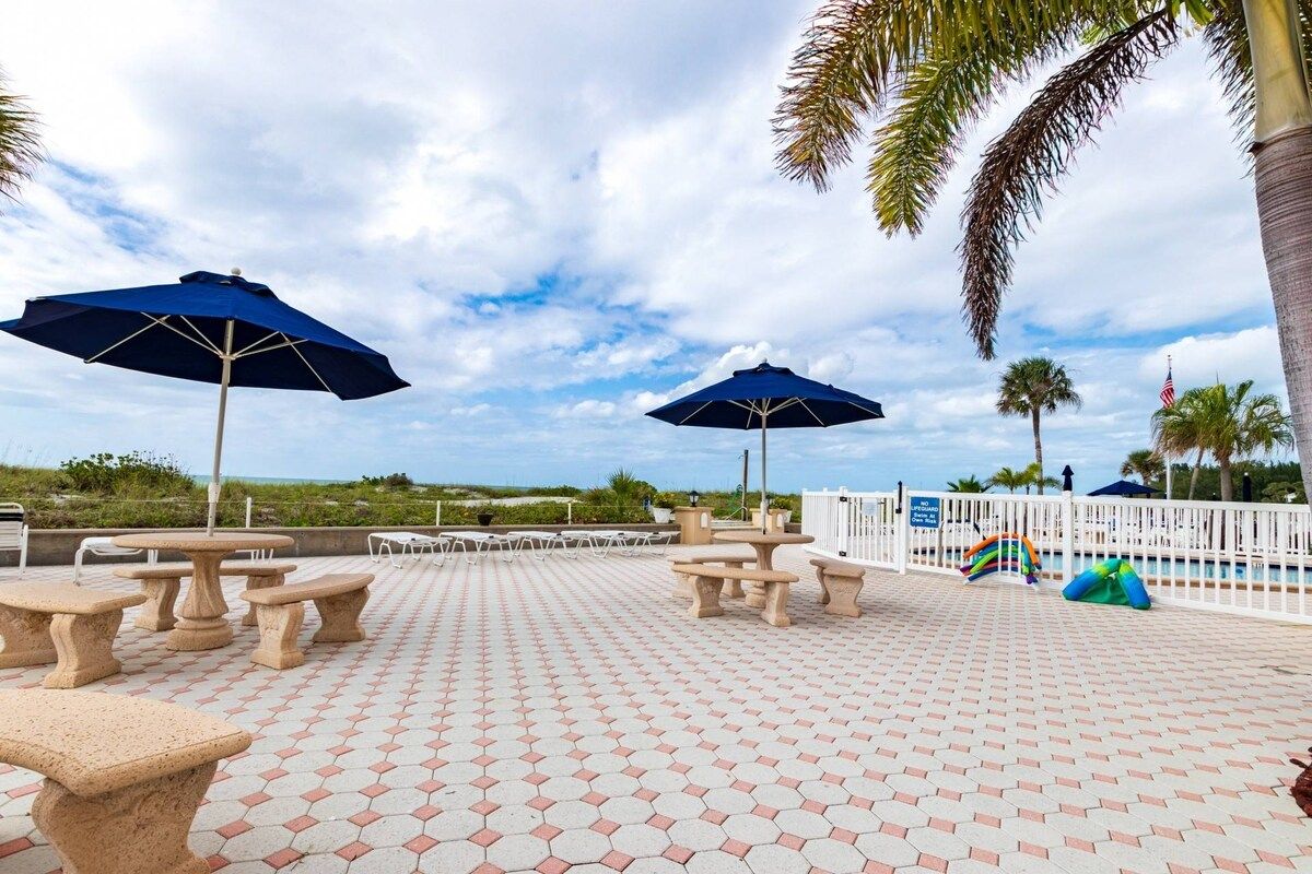 A poolside area with hexagonal tiles, outdoor tables, and umbrellas.