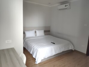 A bedroom with a bed, a bedside table, and an air conditioning unit on the wall. - Himeji Serviced Apartments (Hanoi)