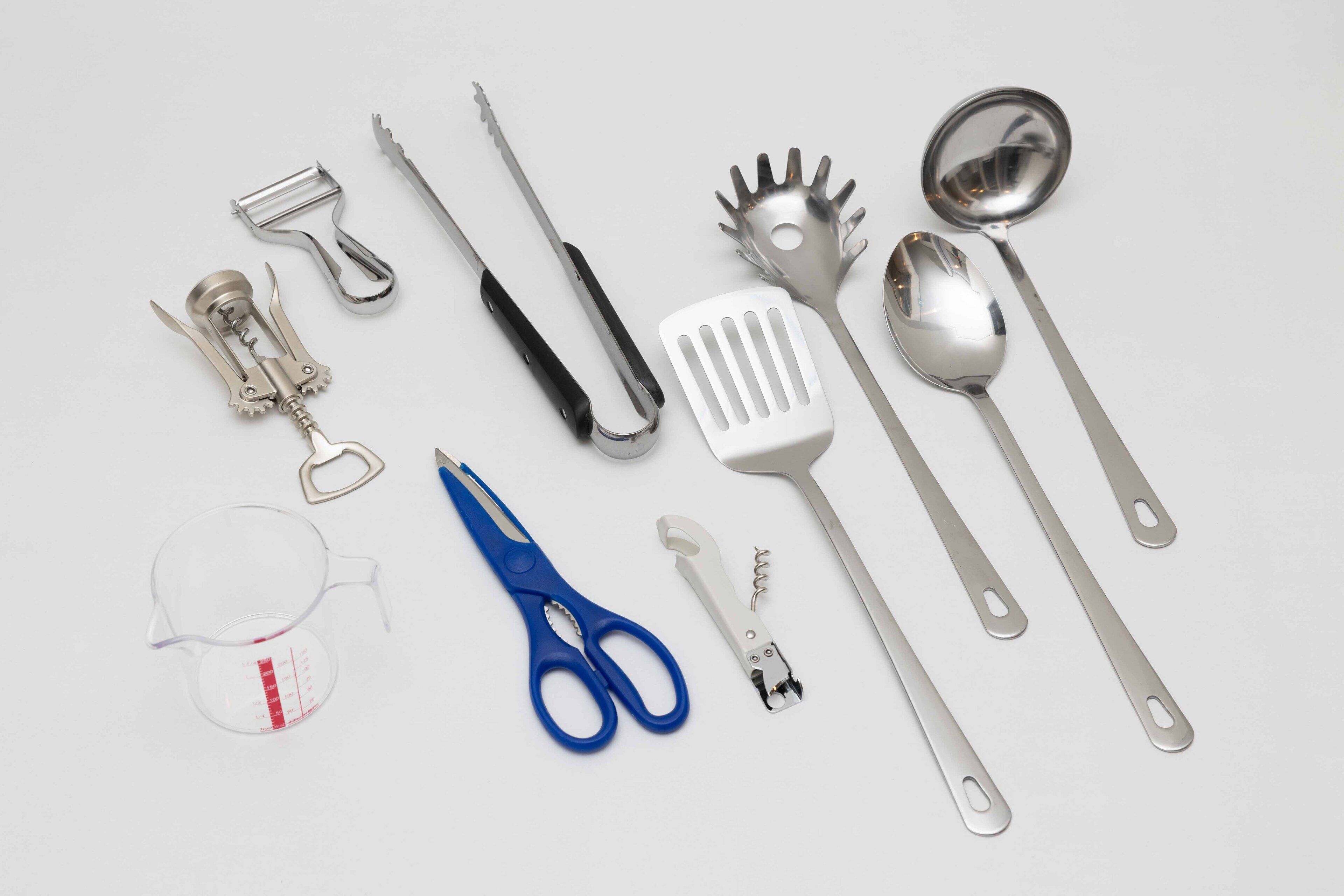 A collection of kitchen utensils and tools including a measuring cup, scissors, and various metal implements.