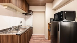 A compact kitchen with wooden cabinets, a stainless steel sink, and a black refrigerator. - Bird Land in Shinsaibashi east (Osaka)