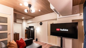 A modern living room with a flat-screen TV, leather sofa, and a small round table. - Bird Land in Shinsaibashi east (Osaka)