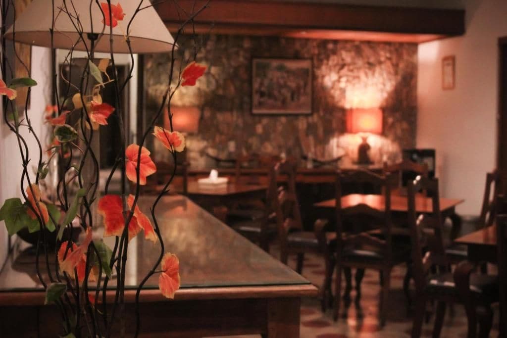A dining area with a long table, chairs, and a vase with flowers.