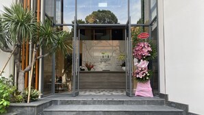 Une entrée moderne avec des portes en verre, un mur de marbre et une enseigne.