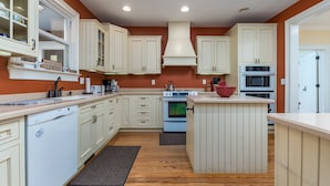 A kitchen with white cabinets, a central island, a stove, and a microwave. - 311 E Market - Two blocks to Lewes Beach! (Lewes)