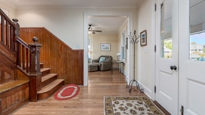 A wooden staircase leading to a living room with a sofa and a ceiling fan. - 311 E Market - Two blocks to Lewes Beach! (Lewes)