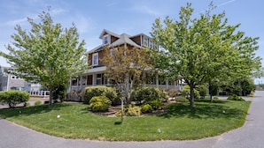 A two-story house with a front porch, surrounded by well-maintained lawns and trees. - 311 E Market - Two blocks to Lewes Beach! (Lewes)