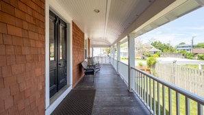 A covered porch with a brick wall, a black door, and a white railing. - 311 E Market - Two blocks to Lewes Beach! (Lewes)