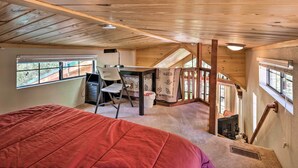 Een slaapkamer met een groot bed, een bureau en een stoel. Er is een raam en een deur die naar een andere kamer leidt.