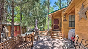 Een houten chalet met een veranda, zitplaatsen buiten en een barbecuehoek.