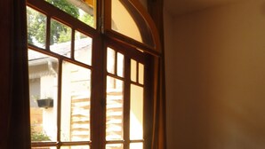 Une pièce avec une porte et une fenêtre en bois, une chaise avec des coussins et un plancher en bois.