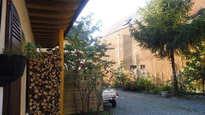 Un espace extérieur abrité, avec un chemin de gravier, un camion et une pile de bois de chauffage.