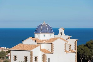 A white building with a blue dome and a view of the sea.