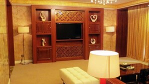 A hotel room with a television, a sofa, a red lamp, and a chandelier. - East Coast Hotel Guangzhou (Guangzhou)