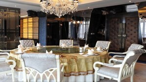 A dining area with a round table, white upholstered chairs, and a chandelier. - East Coast Hotel Guangzhou (Guangzhou)