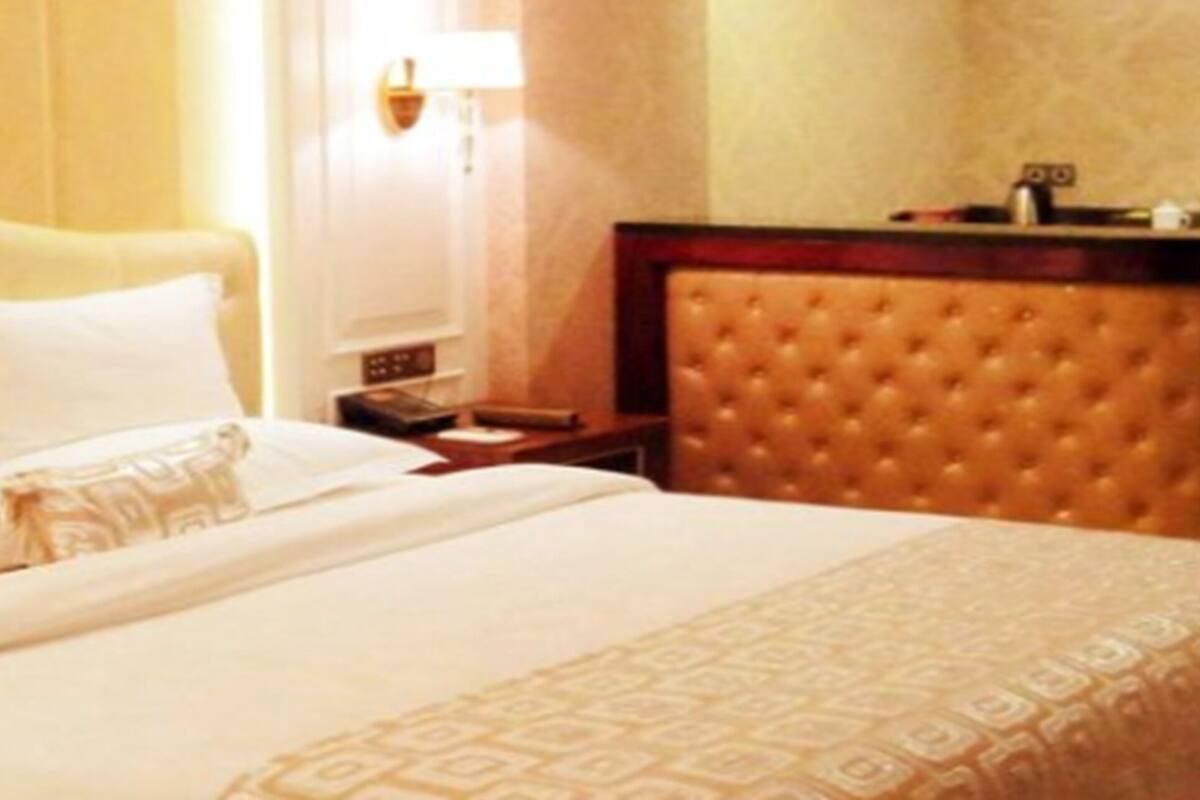 A hotel room with a large bed, a headboard, a bedside table, and a nightstand.
