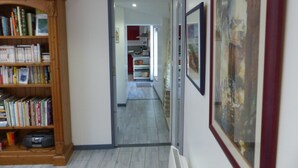 A hallway with a bookshelf, a door leading to a kitchen, and a framed picture on the wall. - Gîte 4 persons; Autour d'un Puits (Marsilly)