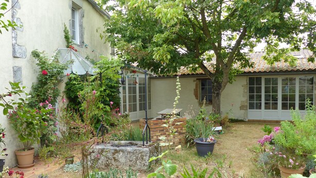 A garden with various potted plants and a brick structure. - Gîte 4 persons; Autour d'un Puits (Marsilly)