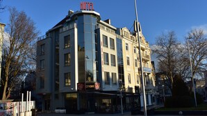 Un edificio en esquina con un letrero que dice 'HOTEL', un letrero que dice 'CITYCAFE' y un letrero que dice 'ENGLISH ACADEMY'.