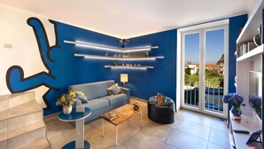 Una sala de estar moderna con una pared azul decorativa, un sofá, una mesa de centro y una estantería.