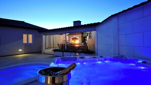 A hot tub with blue lighting, a patio area with a fire feature, and a bucket with a bottle. - Holiday Home near Trogir (Kastela)