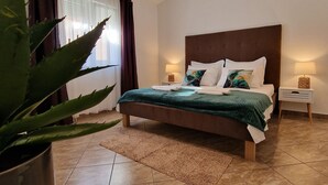 A modern bedroom with a large bed, a potted plant, and a tiled floor. - Holiday Home near Trogir (Kastela)