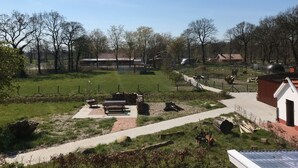 Propiedad campestre con cercado, banco de madera, mesa de picnic y un cobertizo pequeño.