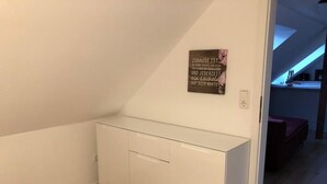 Un mueble empotrado pequeño y blanco en una habitación con suelo de madera y paredes blancas.