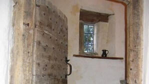 A narrow stone staircase with a wooden handrail, leading to a room with a small window and a shelf above it. - Grade 1 listed Medieval Hall House near the Devon and Cornwall border (Leat)