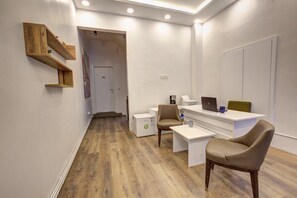 A modern office space with a reception desk, two chairs, a coffee machine, and a small refrigerator. - Maravilloso Hotel Galata (Istanbul)