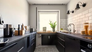 Cozinha moderna com armários escuros, fogão embutido e janela com vista para o verde.