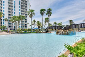 Una gran piscina con palmeras y un edificio de hotel al fondo.