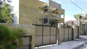 A residential building with a concrete facade, a gated entrance, and a staircase leading to an upper level. - 45C Coco Canopy Sea views Hiking Kiting Beaches Adventure (La Gaulette)
