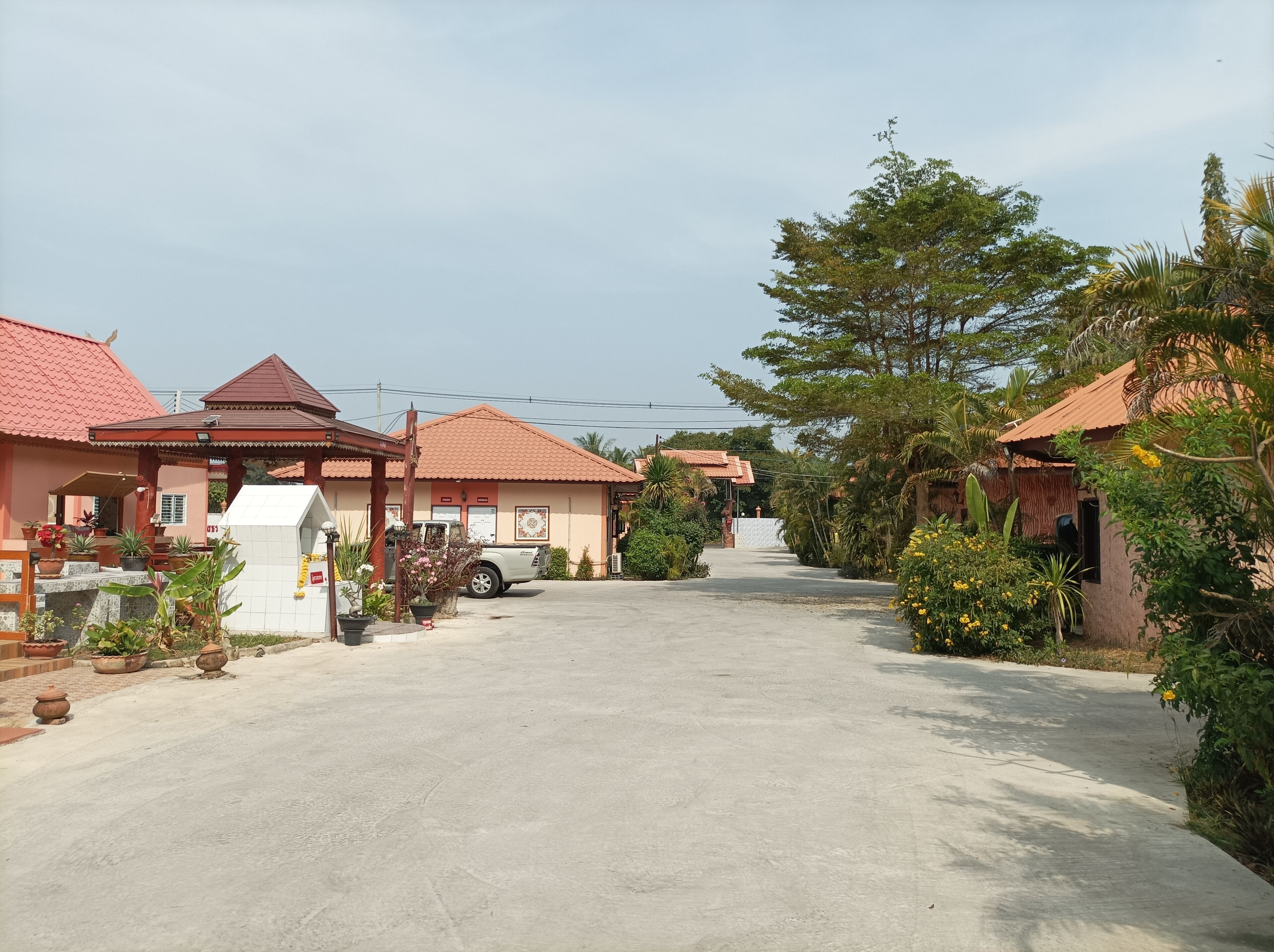 A residential area with houses featuring red-tiled roofs, a paved driveway, and lush greenery.