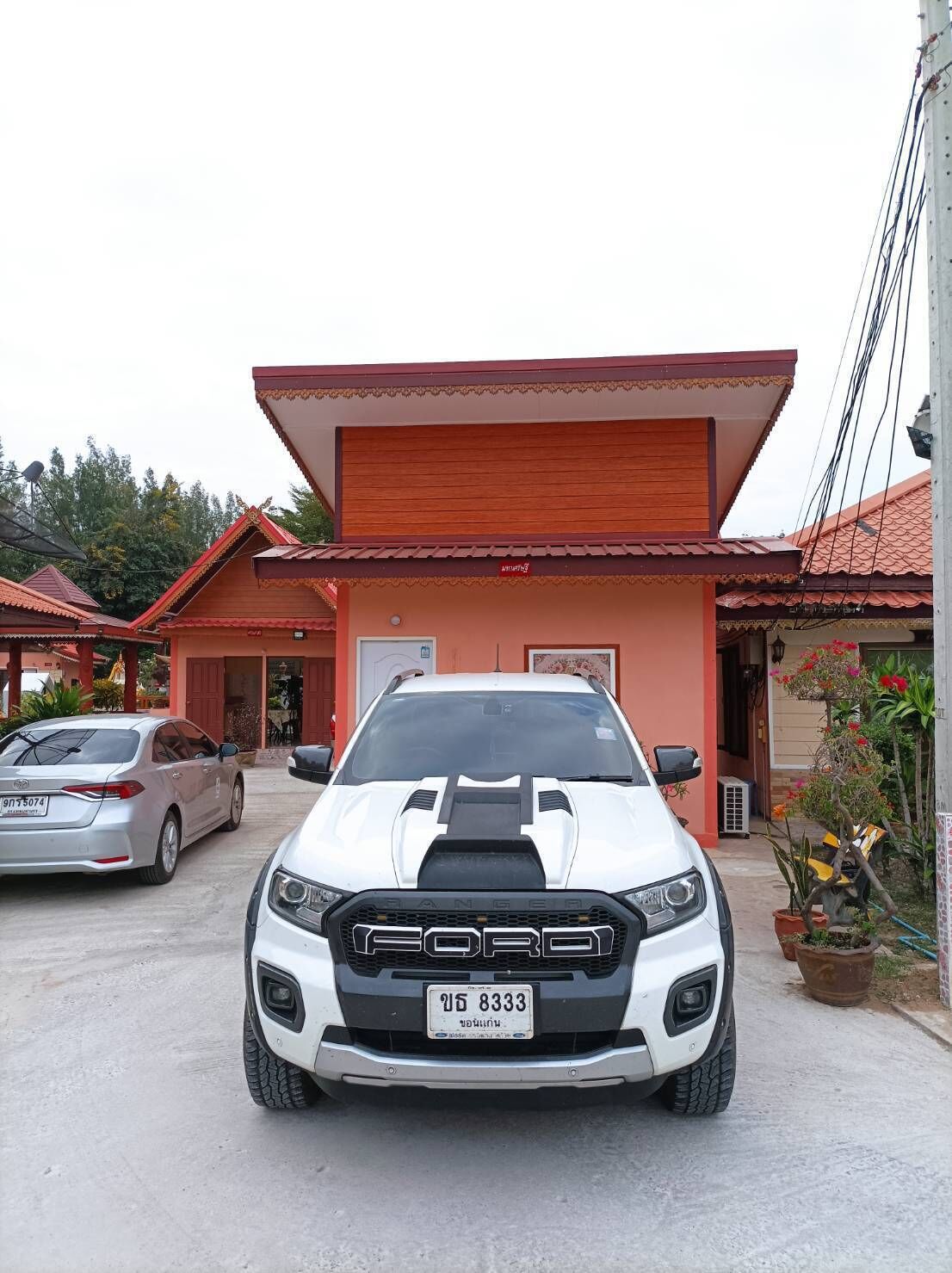A white Ford Ranger parked in front of a building with a red roof and a sign that reads "RANGER".