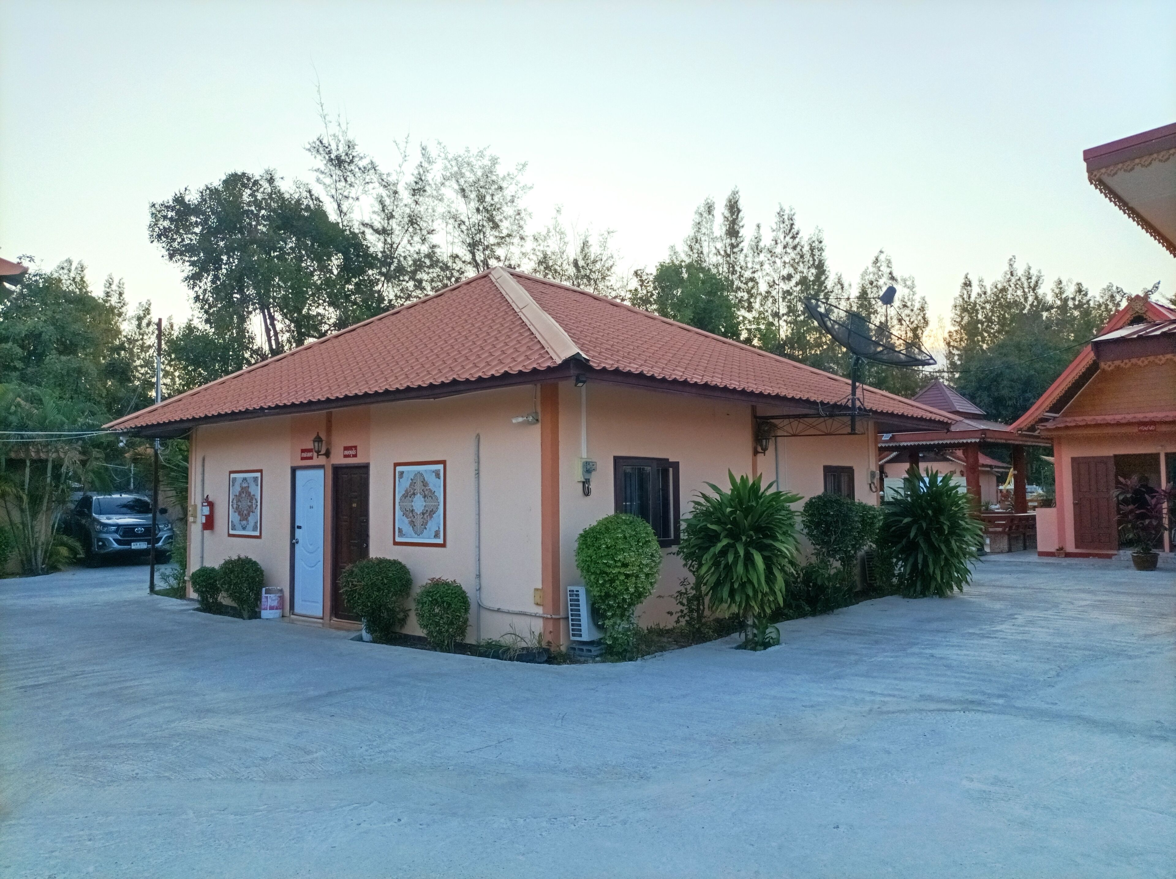 A single-story building with a tiled roof, a small porch, and a parking area.