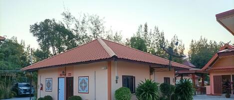 A single-story building with a tiled roof, a small porch, and a parking area.