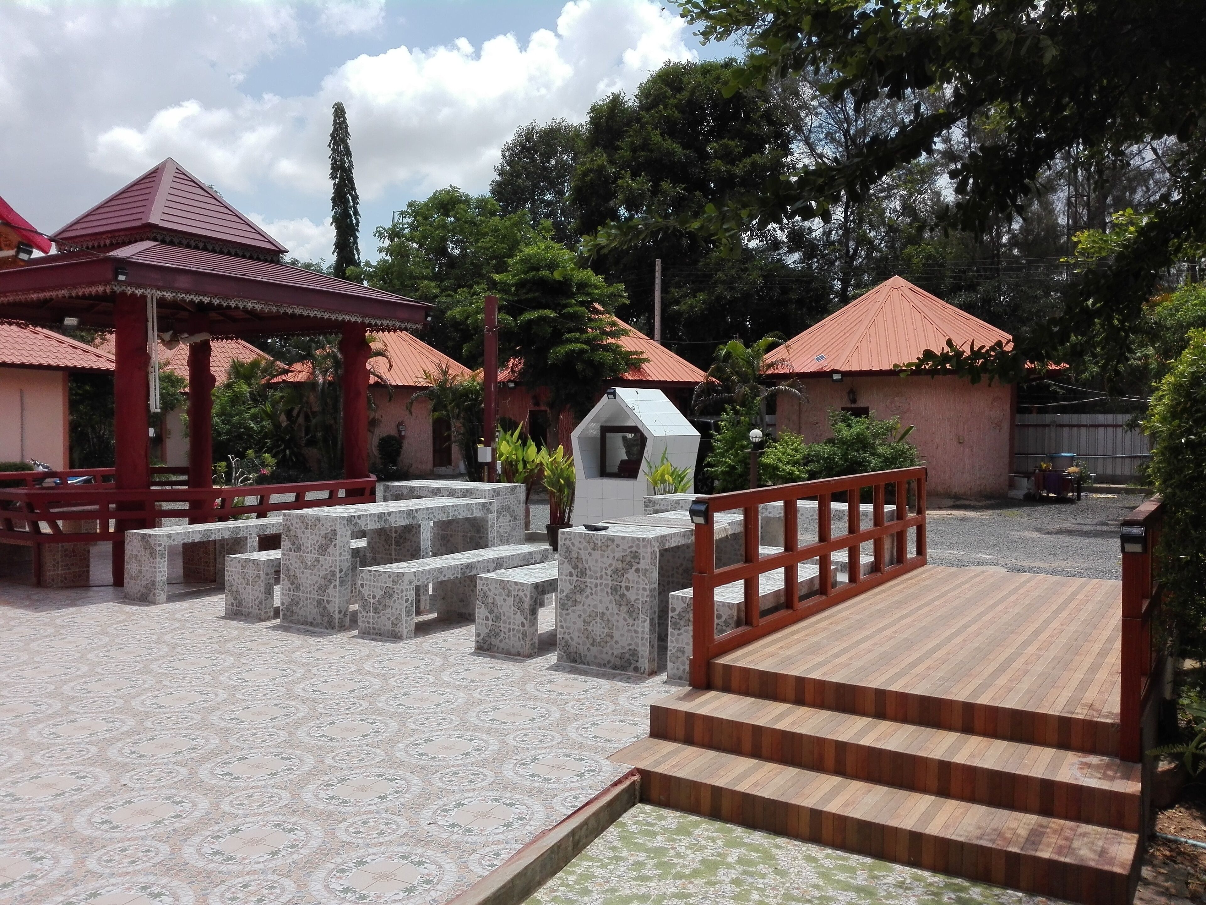 A courtyard with a gazebo, a small kiosk, and a wooden staircase leading to a raised platform.
