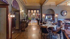 A spacious hotel lobby with wooden flooring, elegant furniture, and a grand staircase leading to the upper floors.