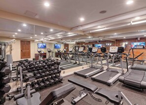 Un gimnasio con cintas de correr, mancuernas y equipo de ejercicio.