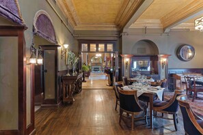 A hotel lobby with a wooden floor, a reception desk, and a dining area with tables and chairs. - The Detroit Club (Detroit)