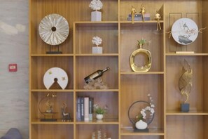 A wooden shelving unit with various decorative items including vases, a clock, and figurines. - GreenTree Inn (Lezhi County Government Branch) (Ziyang)