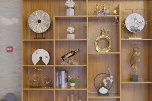Una estantería de madera con diversos objetos decorativos, como jarrones, un reloj y figurillas.