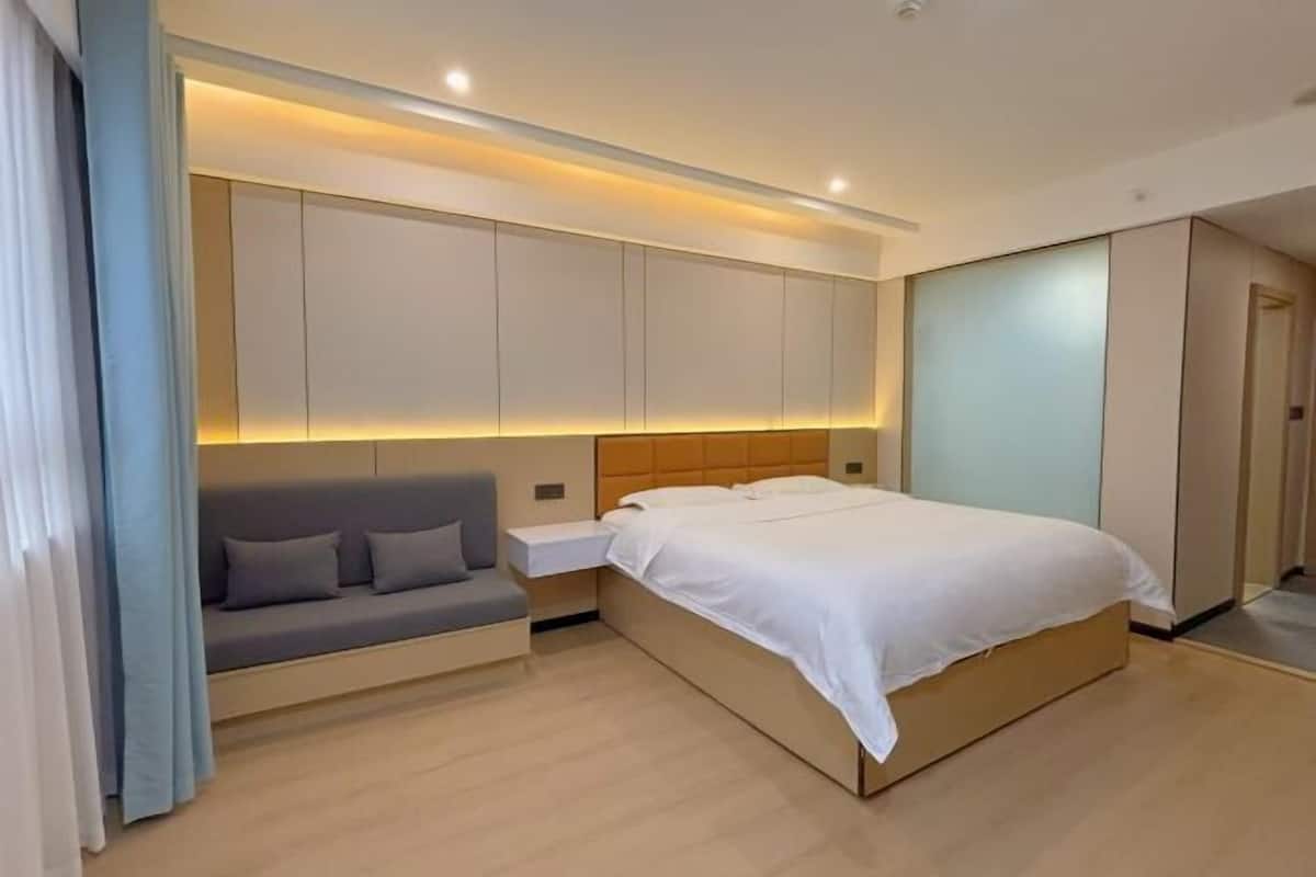 A modern bedroom with a bed, a sofa, and built-in cabinets.